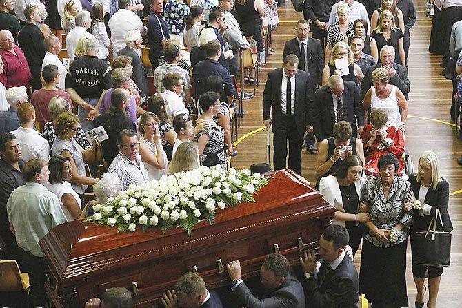 The casket containing Australian cricketer Phillip Hughes is carried past mourners at the end of his funeral service in Macksville
