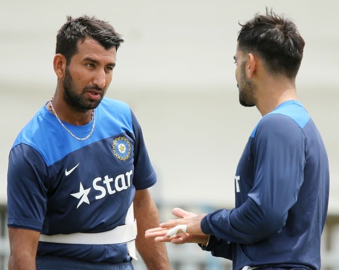 Cheteshwar Pujara, left, speaks to teammate Virat Kohli during a training session
