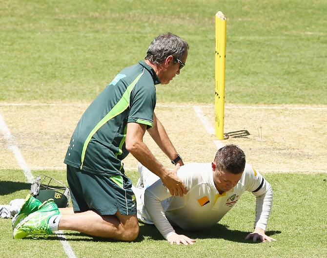 Michael Clarke of Australia is checked by team doctor Peter Brukner before getting off the field retired hurt