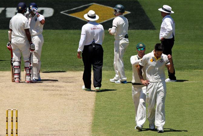  Michael Clarke speaks to Mitchell Johnson after his bouncer hit Virat Kohli on the helmet