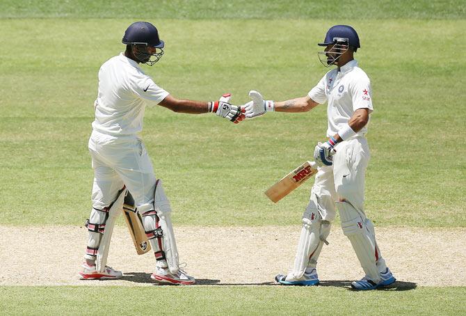 Virat Kohli congratulates teammate Cheteshwar Pujara after completing his half-century on Thursday