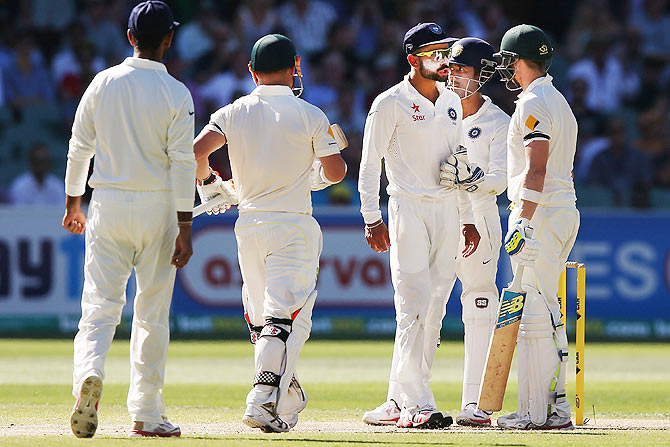 Virat Kohli of India is held back by 'keeper Wriddhiman Saha as he exchanges words with Steve Smith on Friday