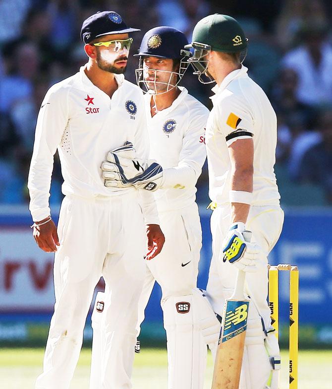 Virat Kohli of India is held back by keeper Wriddhiman Saha as he has words with Steve Smith   of Australia