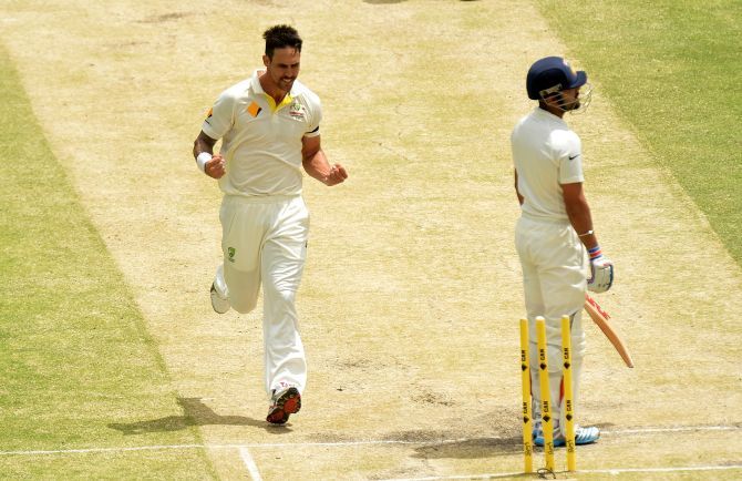 Mitchell Johnson of Australia takes the wicket of Virat Kohli