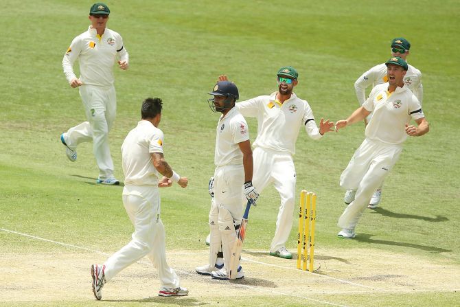 Mitchell Johnson of Australia celebrates with team mates after taking the wicket of Rohit Sharma 