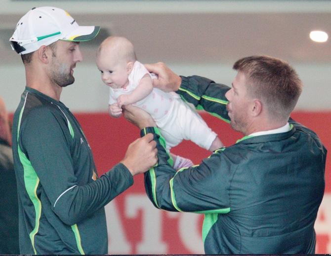 David Warner of Australia plays with his baby Ivy Mae Warner as Nathan Lyon looks on