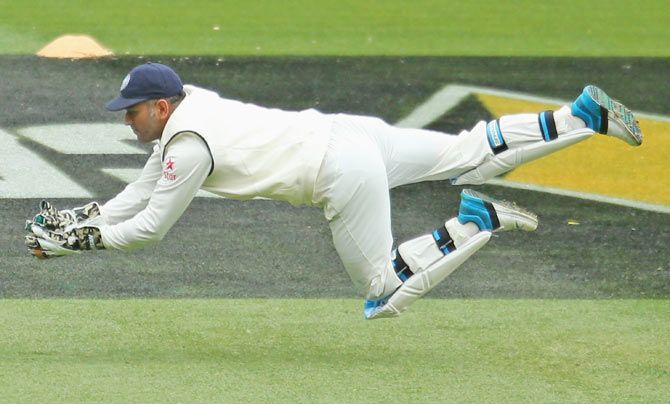 MS Dhoni of India dives to take a catch to dismiss Joe Burns of Australia on Monday