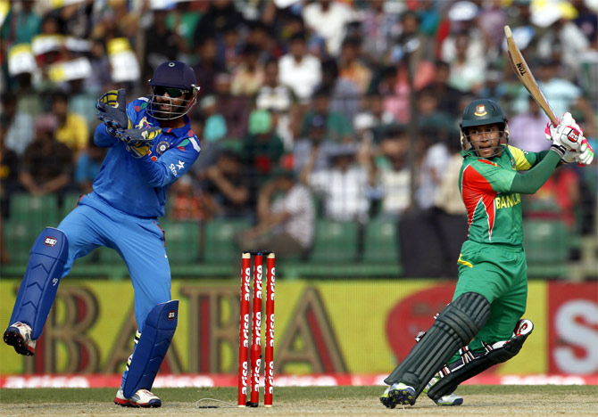 Mushfiqur Rahim hits a shot as Dinesh Karthik looks on