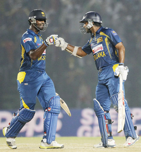 Sri Lanka's Thisara Perera congratulates Kumar Sangakkara (right) as he scores a century against India in their Asia Cup match in Fatullah