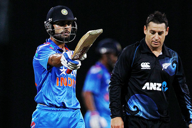 Virat Kohli of India celebrates his half century as Nathan McCullum of New Zealand looks on