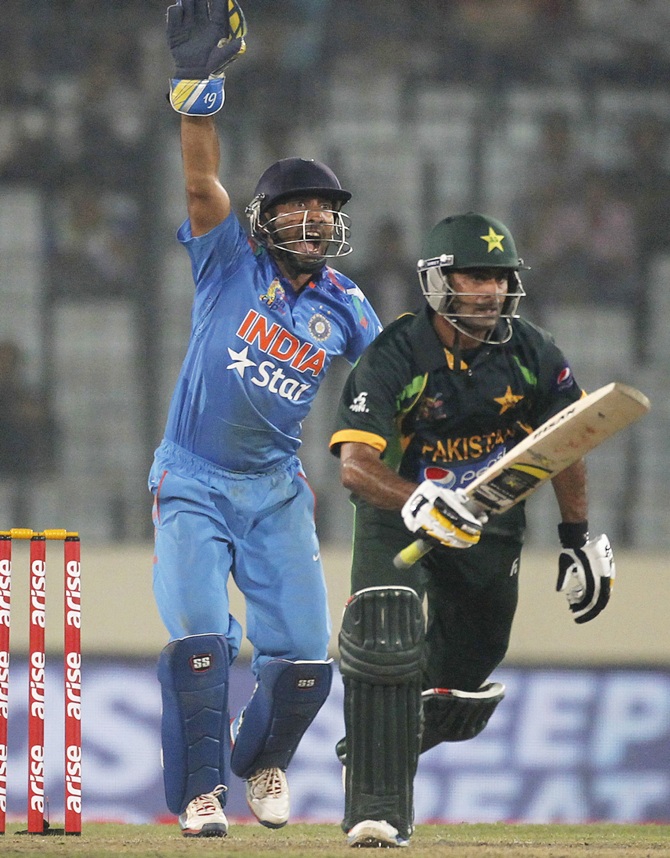 Pakistan's Mohammad Hafeez runs between the wickets as India's wicketkeeper Dinesh Karthik, left, reacts