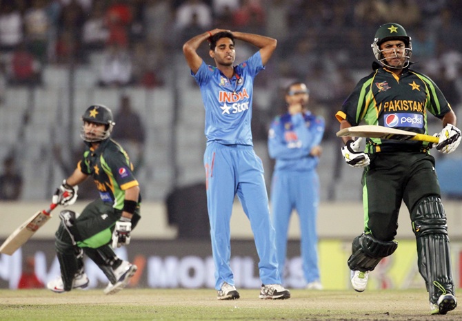 Pakistan's Ahmed Shahzad,left, and Sharjeel Khan run between the wickets as India's bowler Bhuvneshwar Kumar watches.