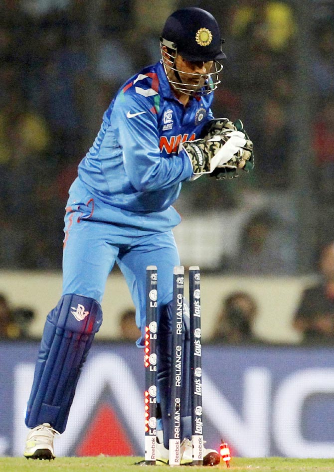India's captain and wicketkeeper Mahendra Singh Dhoni breaks the wicket to dismiss Pakistan's Ahmed Shehzad