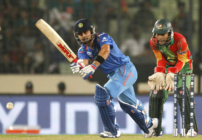 Virat Kohli plays a ball as Bangladesh's captain and wicketkeeper Mushfiqur Rahim (right) watch