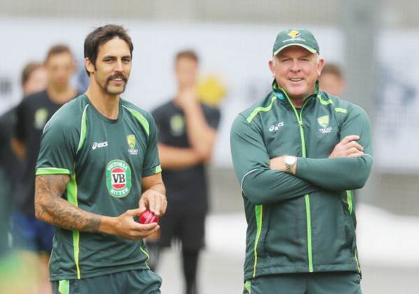 Mitchell Johnson of Australia prepares to bowl as bowling coach Craig McDermott looks on during an Australian Ashes training session at the Melbourne Cricket Ground on December 23, 2013 