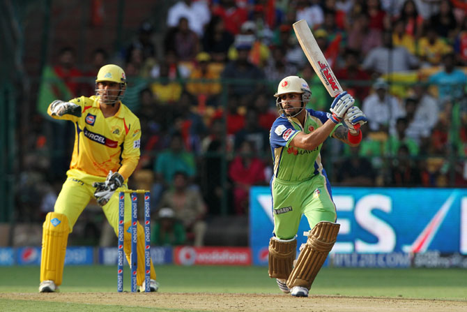 Virat Kohli hits a shot as Dhoni looks on