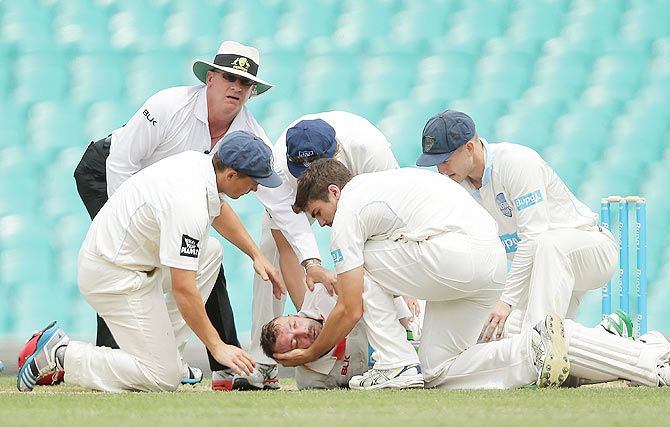 Phillip Hughes of South Australia is helped by New South Wales players after falling to the ground after being struck in the head by a delivery during day one of the Sheffield Shield match between New South Wales and South Australia at Sydney Cricket Ground on Tuesday