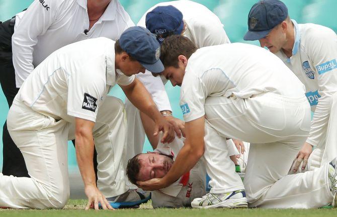 Phillip Hughes of South Australia is helped by New South Wales players