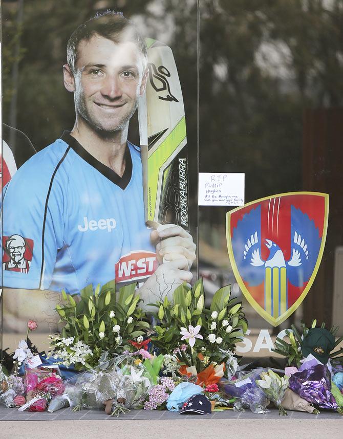 Tributes are seen lying next to a photograph of Phil Hughes outside the Adelaide Oval on Friday