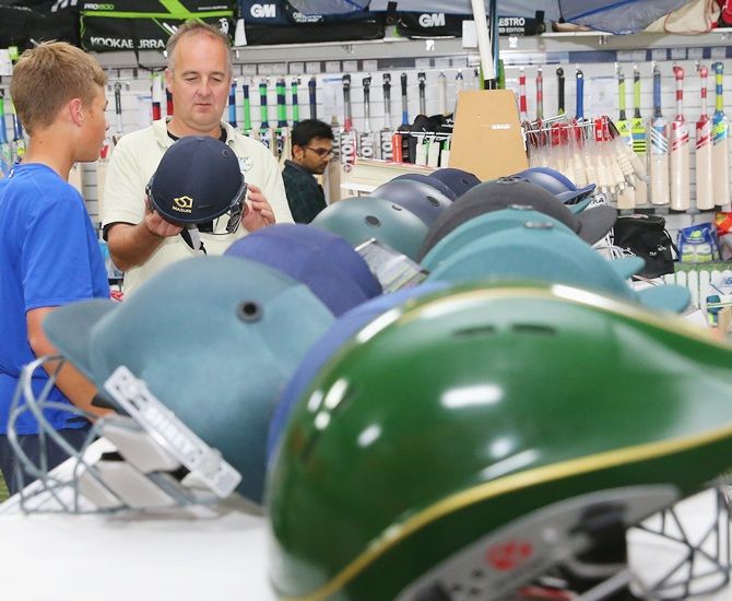 A father and son look at cricket helmets
