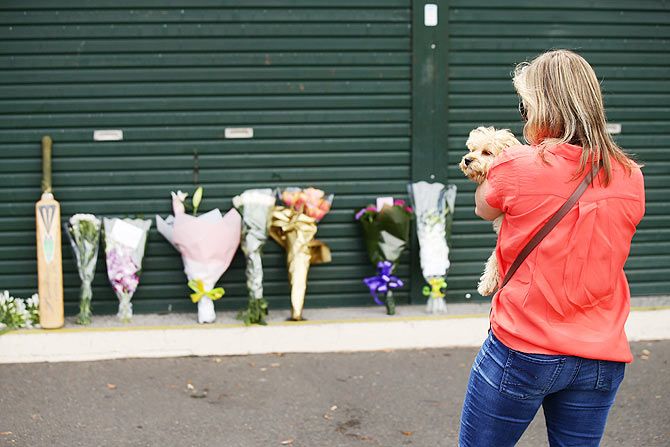 A woman leaves flowers to pay her respects to Phillip Hughes at the Sydney Cricket Ground members entrance on Friday