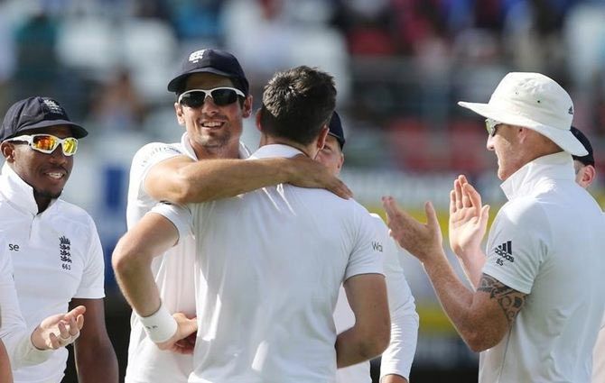 England's James Anderson celebrates with Alastair Cook after taking the wicket of West Indies' Denesh Ramdin, to  break the Ian Botham's record for most Test wickets by an England player