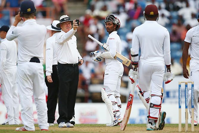 Denesh Ramdin of West Indies looks at umpire Bruce Oxenford as play is suspended due to bad light