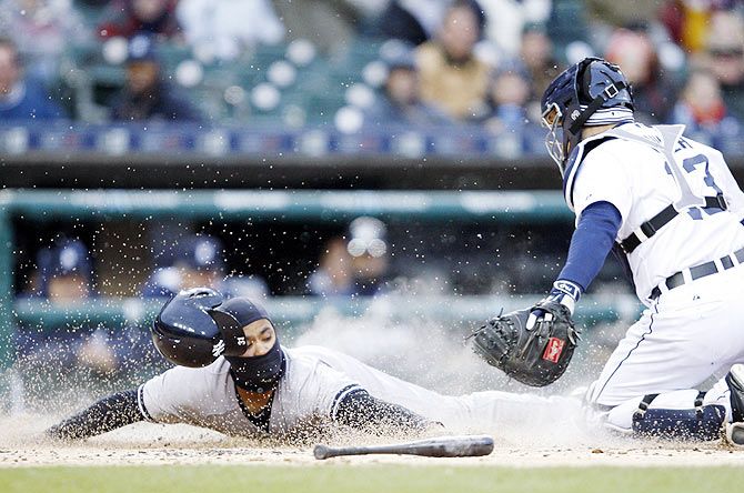 New York Yankees second baseman Gregorio Petit (31) slides safely at home plate as Detroit Tigers catcher Alex Avila (13) misses the tag during the first inning at Comerica Park in Detroit on April 22