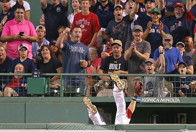 Mookie Betts #50 of the Boston Red Sox falls over the bullpen after catching a ball hit by Jose Abreu #79 of the Chicago White Sox, which was ruled a home run after an official review showed the ball was dropped, in the sixth inning at Fenway Park in Boston, Massachusetts, on July 28.