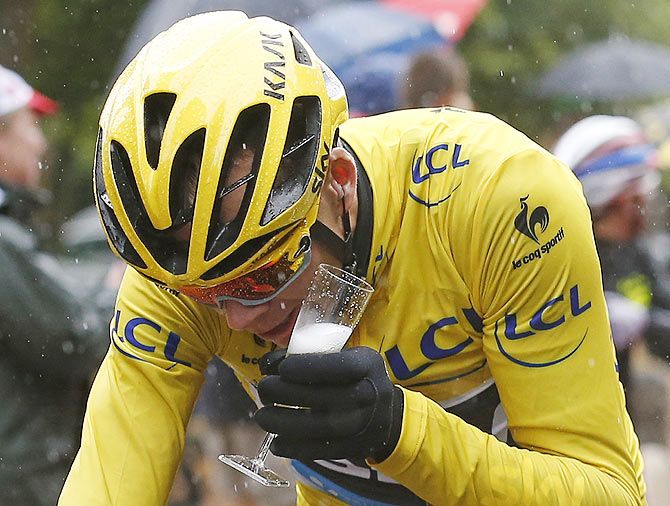 Team Sky rider Chris Froome of Britain, the race overall leader's yellow jersey, holds a glass of champagne as he cycles during the 109.5-km (68 miles) final 21st stage