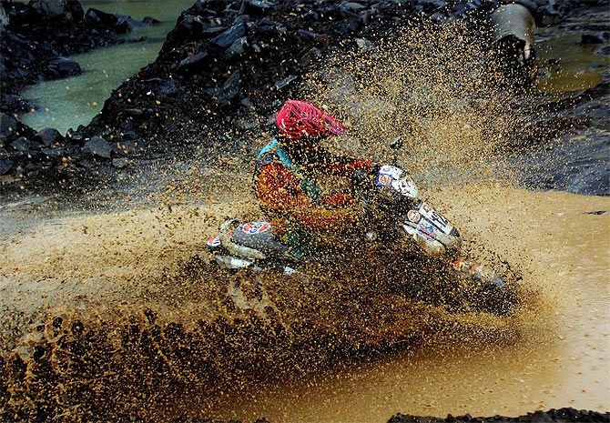 A rider is drenched in slush as he tries to negotiate a puddle