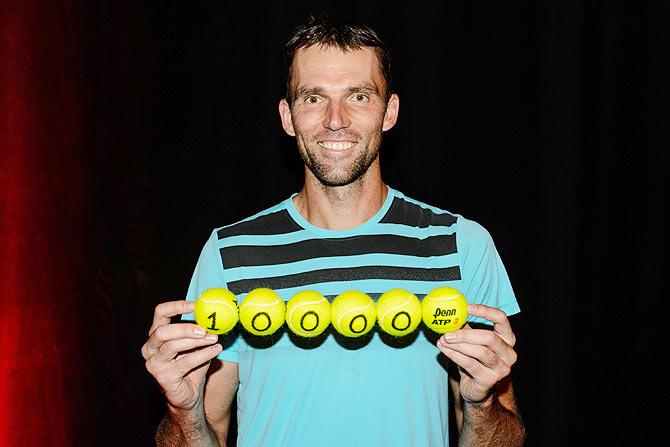 Croatia's Ivo Karlovic holds up tennis balls marking his feat of serving 10,000 aces, becoming only the second player in history to do so