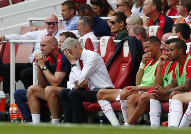 Arsenal manager Arsene Wenger looks dejected as assistant manager Steve Bould looks on during their season-opening loss against West Ham