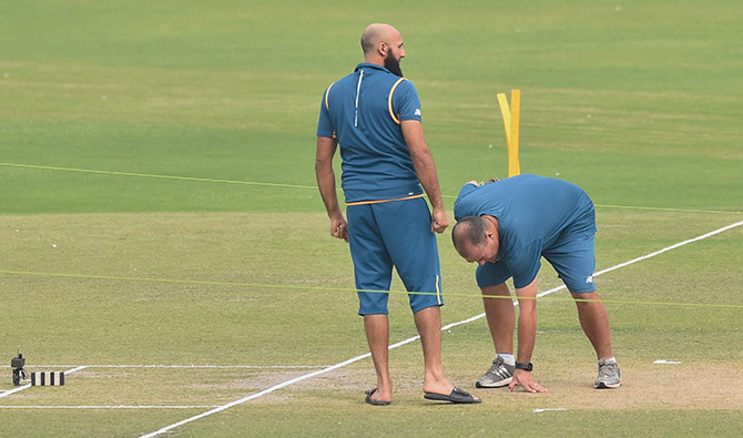 South African captain Hashim Amla with an official inspects the pitch 