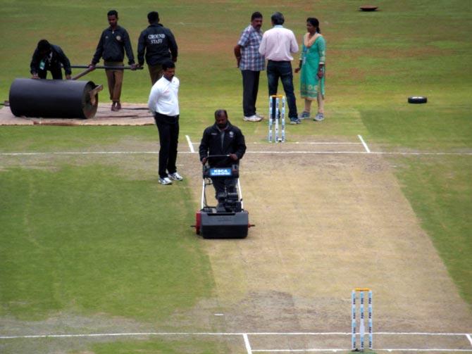 Groundstaff work on the pitch in Bangalore 