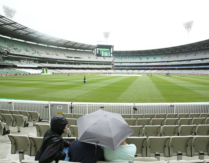 Fans wait as rain delays play during day four of the Third Test match between Australia and India at   Melbourne Cricket Ground on December 29, 2014 in Melbourne
