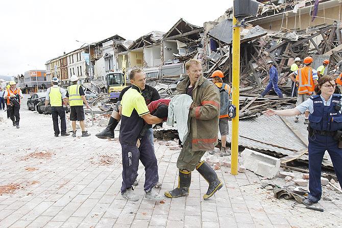 Rescuers workers carry the body of a deceased woman on February 22, 2011 in Christchurch, New Zealand