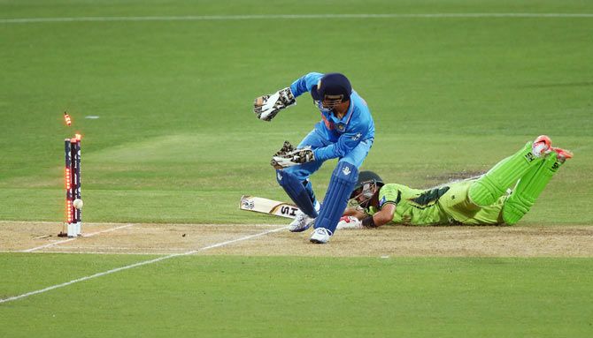Ahmad Shahzad of Pakistan makes his ground as India's Mahendra Singh Dhoni tries to run him out during their match at the Adelaide Oval on February 15