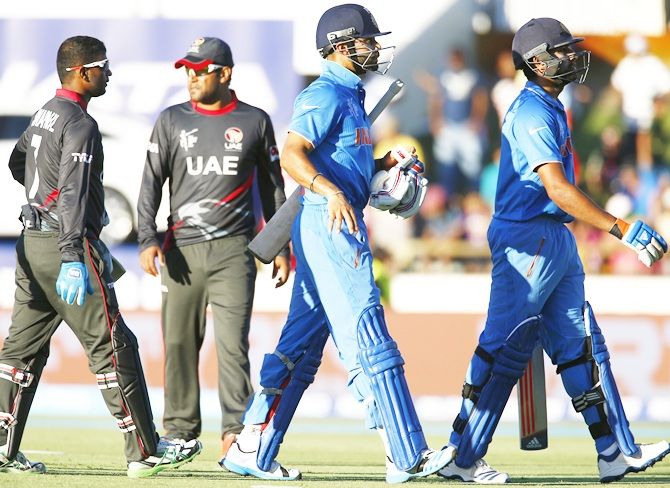Virat Kohli, second from right, and Rohit Sharma walk off the field during a break in play against the UAE. David Gray/Reuters