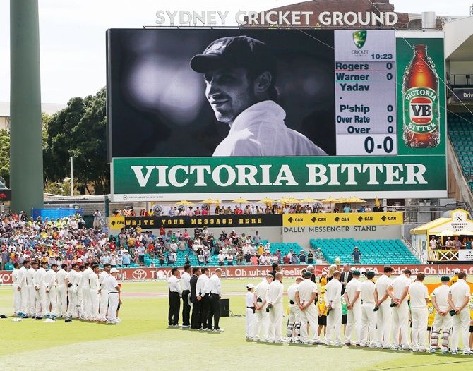 Australia and India teams pay respects in front of a big screen