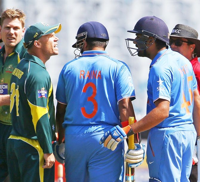 Umpires (in red) and Australia's James Faulkner, second left, watch as Australia's David Warner, third left, argues with India's Rohit Sharma, second right, during their ODI tri-series match at the Melbourne Cricket Ground