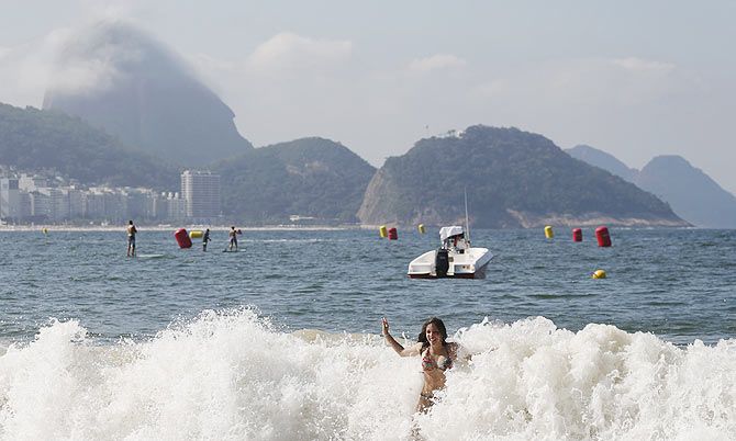 A woman enjoys on Copacabana beach with the Sugarloaf mountain in the background in Rio de Janeiro