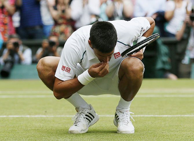 Serbia's Novak Djokovic eats some grass off Centre Court after winning his men's singles final against Switzerland's Roger Federer at the Wimbledon Tennis Championships in London on Sunday