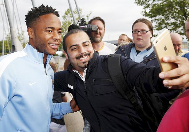 Raheem Sterling poses for selfies with Manchester City supporters as he leaves the club's Etihad Stadium in Manchester on Tuesday