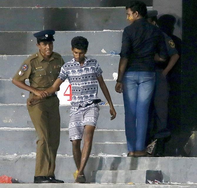 A police officer takes a supporter who was involved in a clash between supporters of the two sides out of the ground