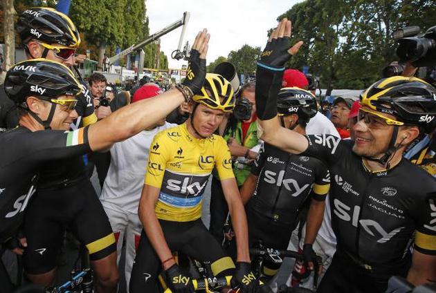 Team Sky rider Chris Froome of Britain (C), the race leader's yellow jersey, celebrates his overall victory with team-mates