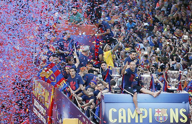 Barcelona's Javier Mascherano and teammates greet fans from an open-top bus during celebration parade in Barcelona on Sunday