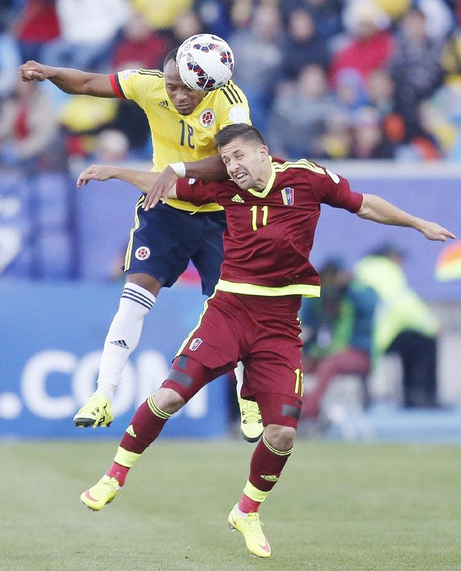 Colombia's Juan Zuniga and Venezuela's Cesar Gonzalez (11) are involved in an aerial challenge