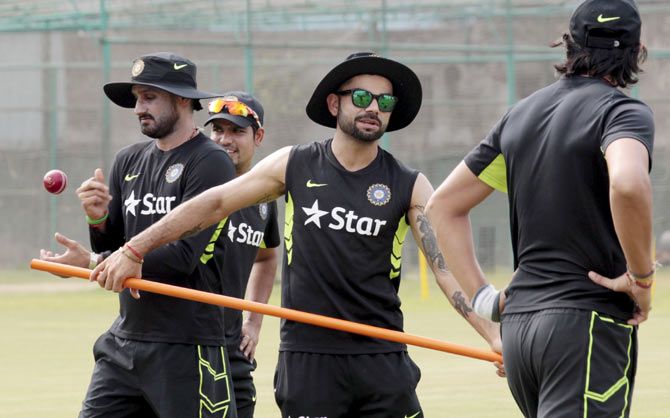 Captain of the Indian cricket team Virat Kohli (C) and bowler Harbhajan Singh (L) during a practice session in Dhaka 