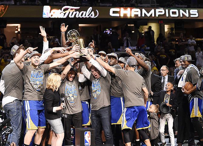 The Golden State Warriors celebrate with the Larry O'Brien Trophy after beating the Cleveland Cavaliers in game six of the NBA Finals at Quicken Loans Arena in Cleveland, Ohio on Tuesday